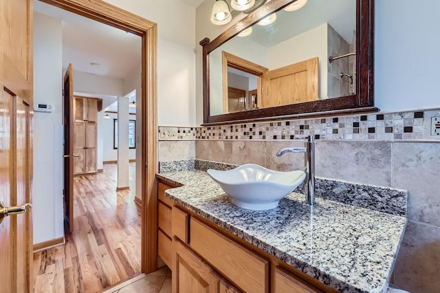 bathroom featuring decorative backsplash, baseboards, wood finished floors, and vanity