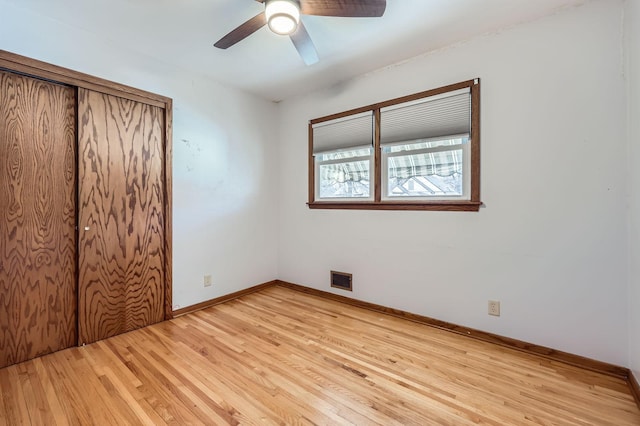 unfurnished bedroom with light wood-type flooring, visible vents, a ceiling fan, a closet, and baseboards