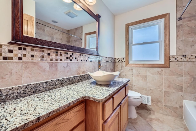 bathroom with visible vents, toilet, a bathing tub, tile walls, and walk in shower