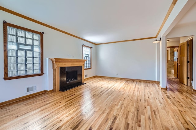 unfurnished living room with visible vents, crown molding, light wood-type flooring, and baseboards