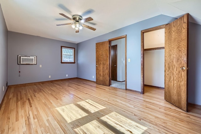 unfurnished bedroom with baseboards, a ceiling fan, light wood-type flooring, and a wall unit AC