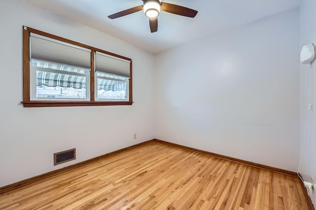 spare room featuring visible vents, a ceiling fan, light wood-type flooring, and baseboards