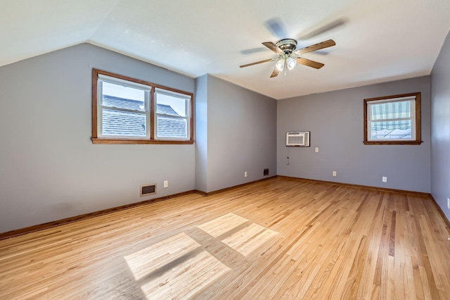 unfurnished room with light wood-style flooring, a wall mounted air conditioner, a ceiling fan, and vaulted ceiling