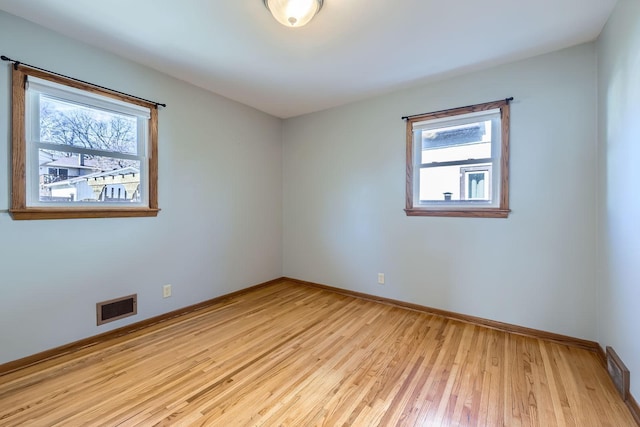 spare room featuring wood finished floors, visible vents, and baseboards