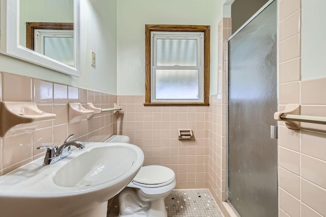 bathroom featuring tile walls, toilet, a stall shower, and a sink