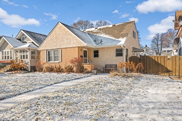 view of front of house with a gate, fence, a sunroom, a shingled roof, and brick siding