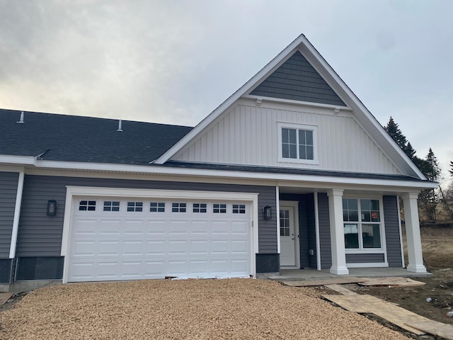 view of front of house featuring board and batten siding, a shingled roof, a porch, a garage, and driveway