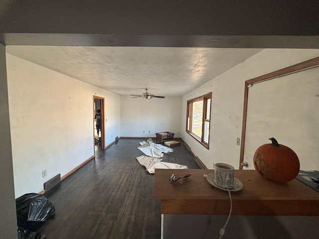 unfurnished living room featuring dark wood-style floors, ceiling fan, and baseboards