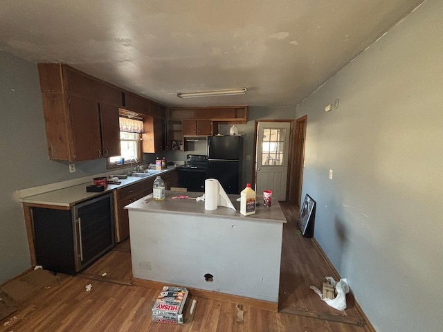 kitchen with wine cooler, black appliances, light countertops, and wood finished floors