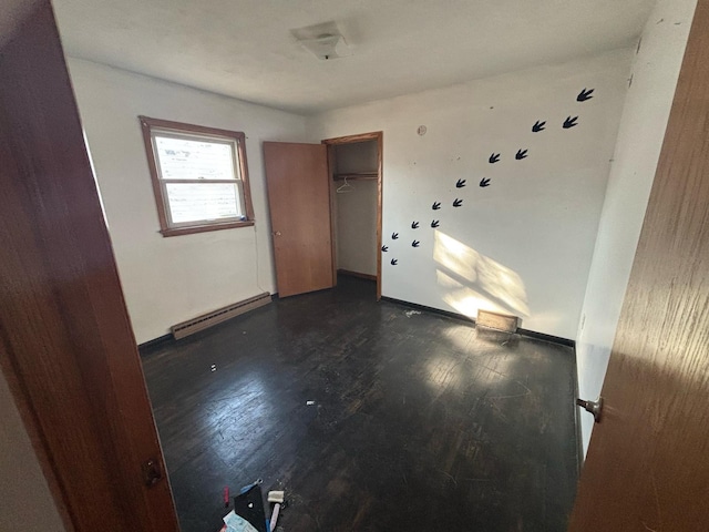 unfurnished bedroom featuring a closet, wood finished floors, baseboards, and baseboard heating