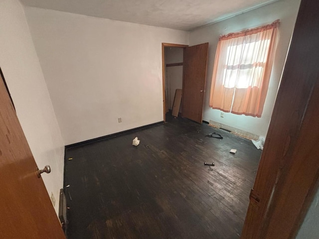 unfurnished bedroom with wood finished floors and baseboards