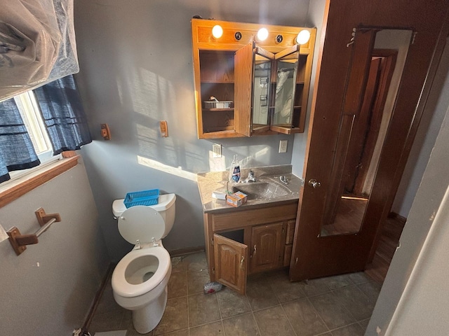 bathroom featuring tile patterned floors, baseboards, toilet, and vanity