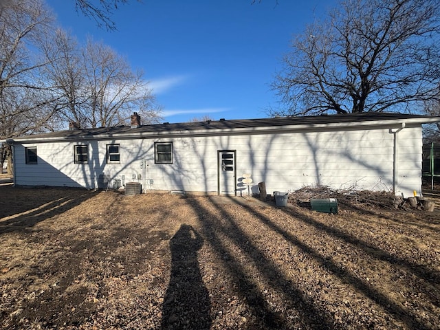 back of house featuring central AC unit and a chimney