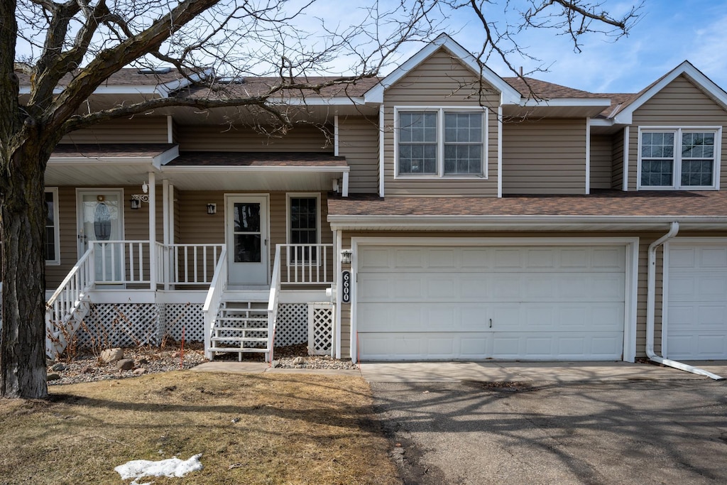 view of front of property featuring aphalt driveway, covered porch, a garage, and roof with shingles