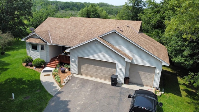 view of front of house with a front lawn, an attached garage, driveway, and roof with shingles