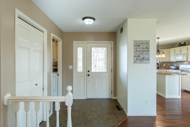 foyer featuring baseboards, visible vents, dark wood-style flooring, and a textured ceiling