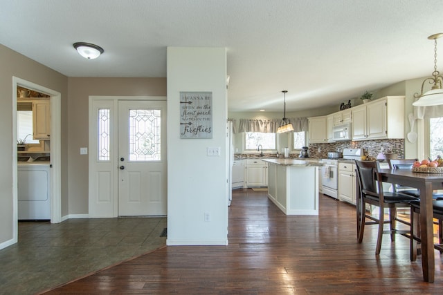 kitchen with tasteful backsplash, a center island, dark wood-type flooring, white appliances, and washer / clothes dryer