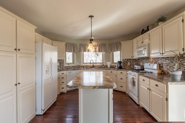 kitchen with white appliances, a center island, dark wood-type flooring, and a sink