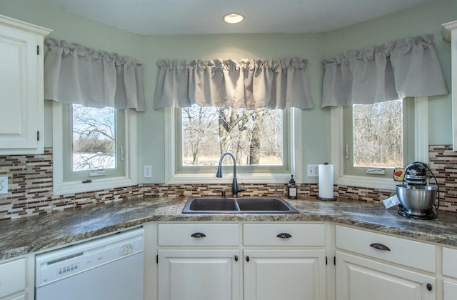 kitchen with dark countertops, dishwasher, decorative backsplash, white cabinetry, and a sink