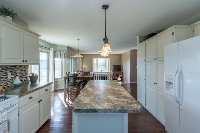 kitchen with white appliances, decorative backsplash, dark wood-type flooring, decorative light fixtures, and a center island