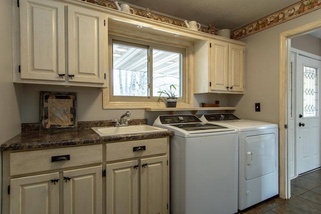 laundry area featuring cabinet space, dark tile patterned flooring, separate washer and dryer, and a sink