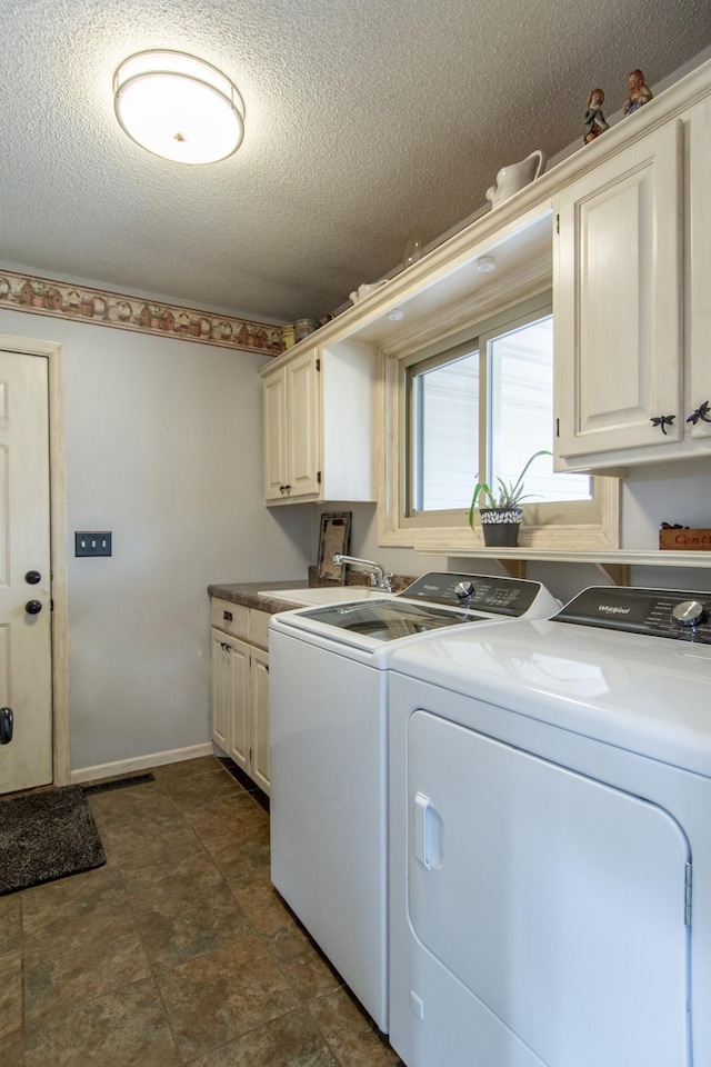 laundry area with baseboards, cabinet space, a textured ceiling, independent washer and dryer, and a sink