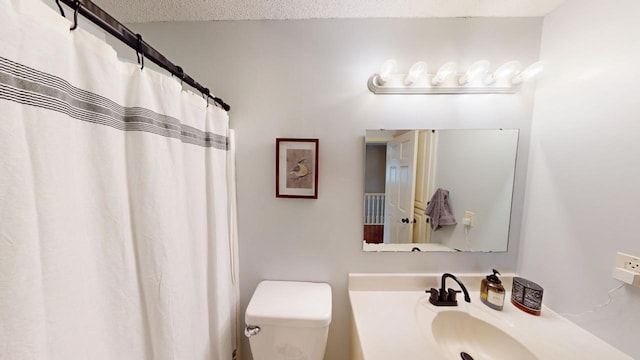 bathroom featuring a textured ceiling, toilet, vanity, and a shower with curtain