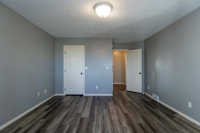 unfurnished bedroom with visible vents, baseboards, a textured ceiling, and dark wood-style flooring