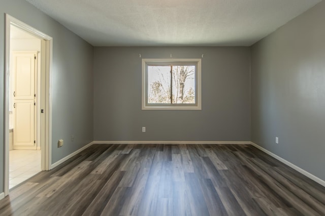 unfurnished room with dark wood-type flooring, baseboards, and a textured ceiling