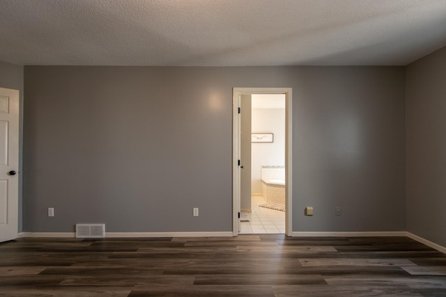 spare room featuring visible vents, baseboards, a textured ceiling, and wood finished floors