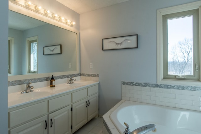 bathroom featuring a garden tub, double vanity, and a sink
