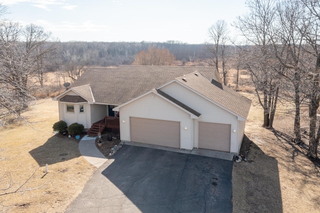 single story home with aphalt driveway, a garage, and roof with shingles