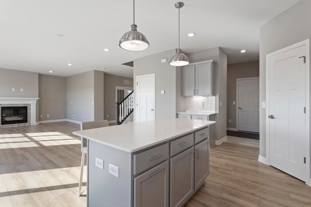 kitchen featuring light wood finished floors, gray cabinets, a center island, and light countertops