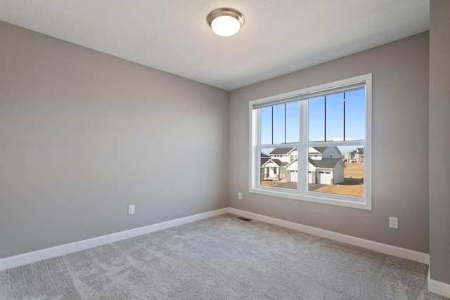 carpeted spare room featuring visible vents, baseboards, and a textured ceiling