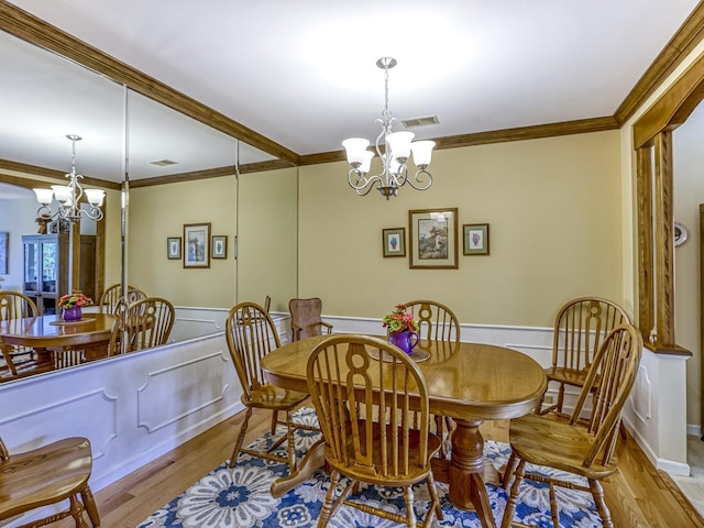 8621 Basswood Rd Unit 33, Eden Prairie, MN 55344 - dining area with a wainscoted wall, wood finished floors, visible vents, ornamental molding, and an inviting chandelier