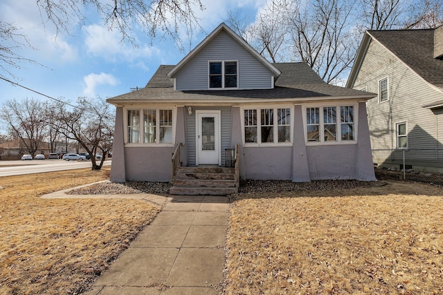 bungalow-style house with stucco siding, fence, a shingled roof, and entry steps