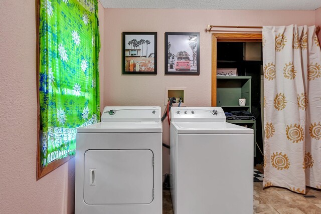 laundry area with a textured wall and washer and clothes dryer
