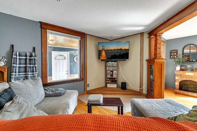 living area with a fireplace, wood finished floors, a textured ceiling, and baseboards