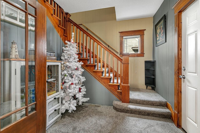 stairs with carpet flooring and a decorative wall
