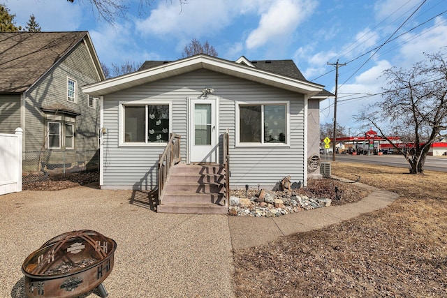bungalow-style house with a fire pit, entry steps, and fence
