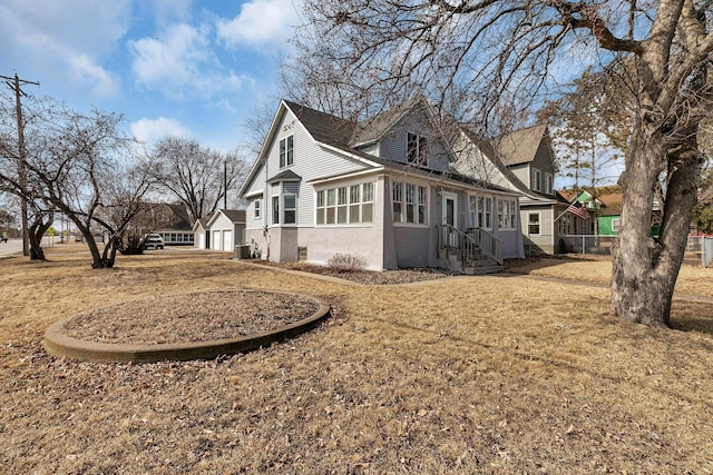 view of side of home featuring entry steps, a detached garage, and stucco siding