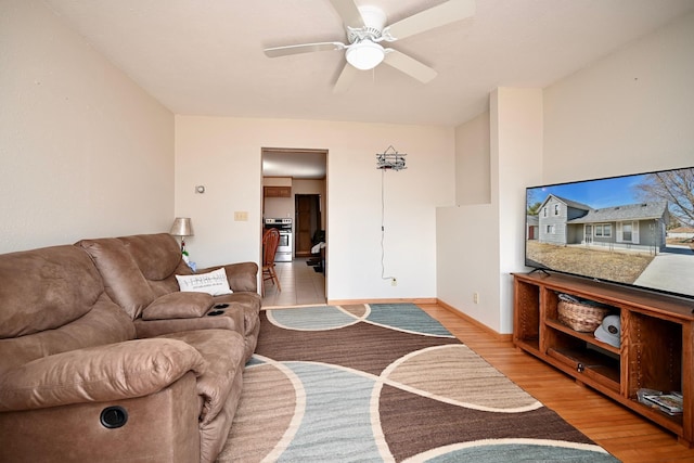 living room with light wood-style flooring, baseboards, and a ceiling fan