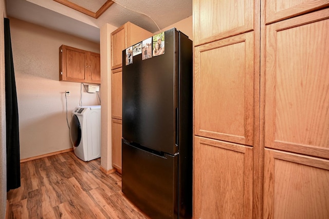 kitchen featuring baseboards, light wood-type flooring, washer / dryer, freestanding refrigerator, and a textured ceiling