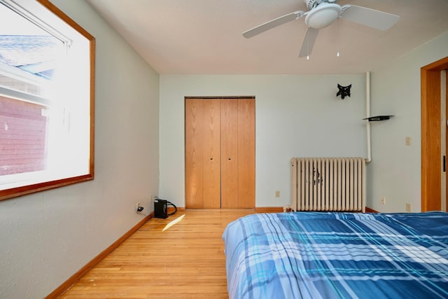 bedroom with light wood-type flooring, a closet, radiator, baseboards, and ceiling fan