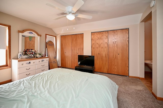 carpeted bedroom with lofted ceiling, baseboards, multiple closets, and ceiling fan