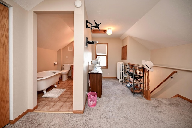 full bath featuring radiator, baseboards, lofted ceiling, tile patterned floors, and a soaking tub