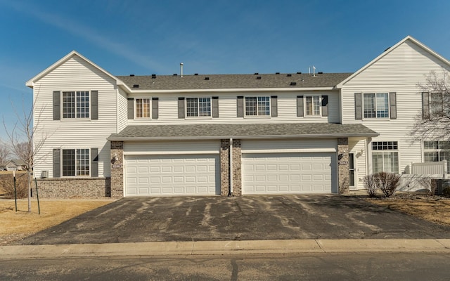 view of front facade featuring aphalt driveway, brick siding, roof with shingles, and a garage