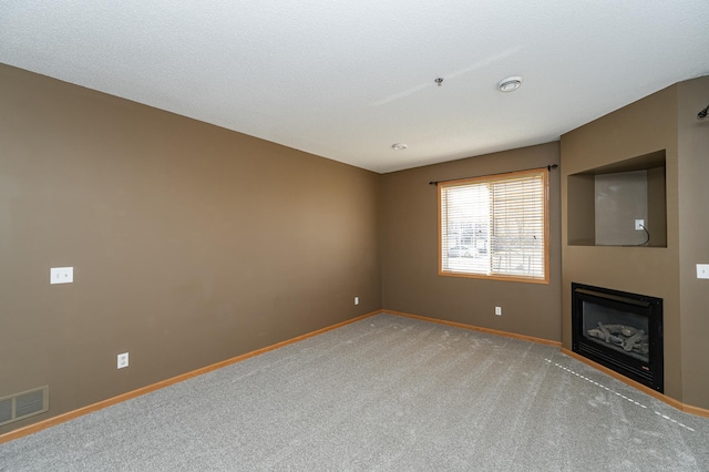 unfurnished living room featuring visible vents, baseboards, carpet floors, and a fireplace