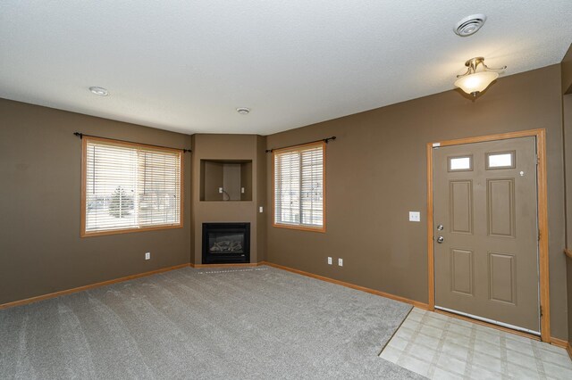 interior space featuring a glass covered fireplace, visible vents, and baseboards