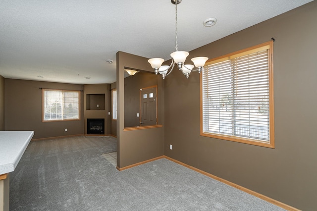 interior space featuring an inviting chandelier, a fireplace, baseboards, and carpet